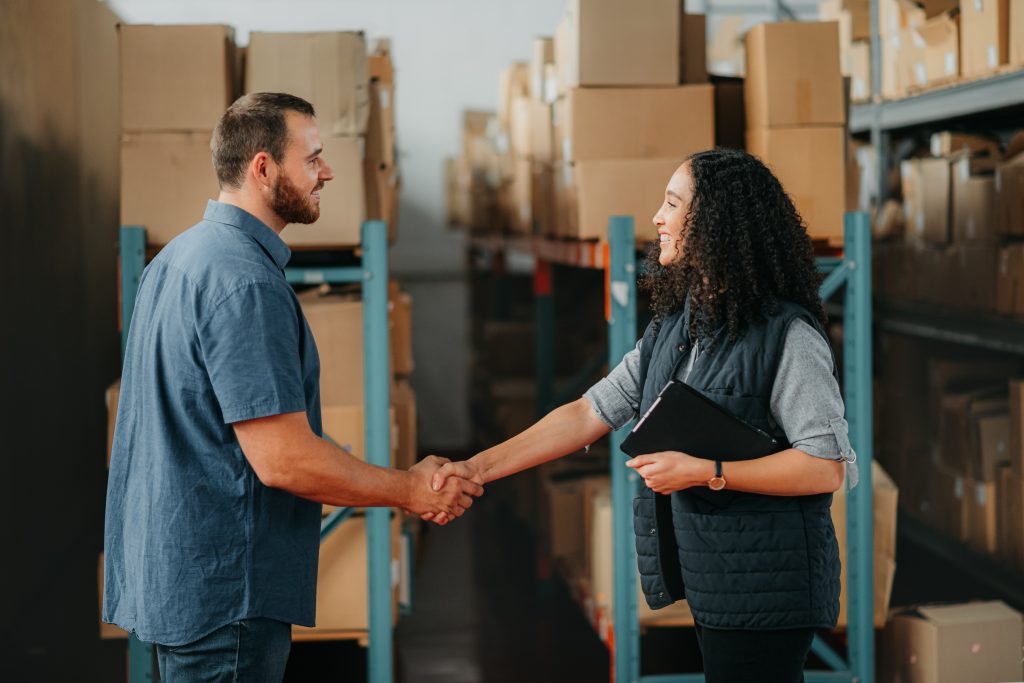Shipping, supply chain and delivery partner with handshake for partnership, support and thank you in a warehouse. Box logistics or stock factory employee with teamwork, collaboration business meeting