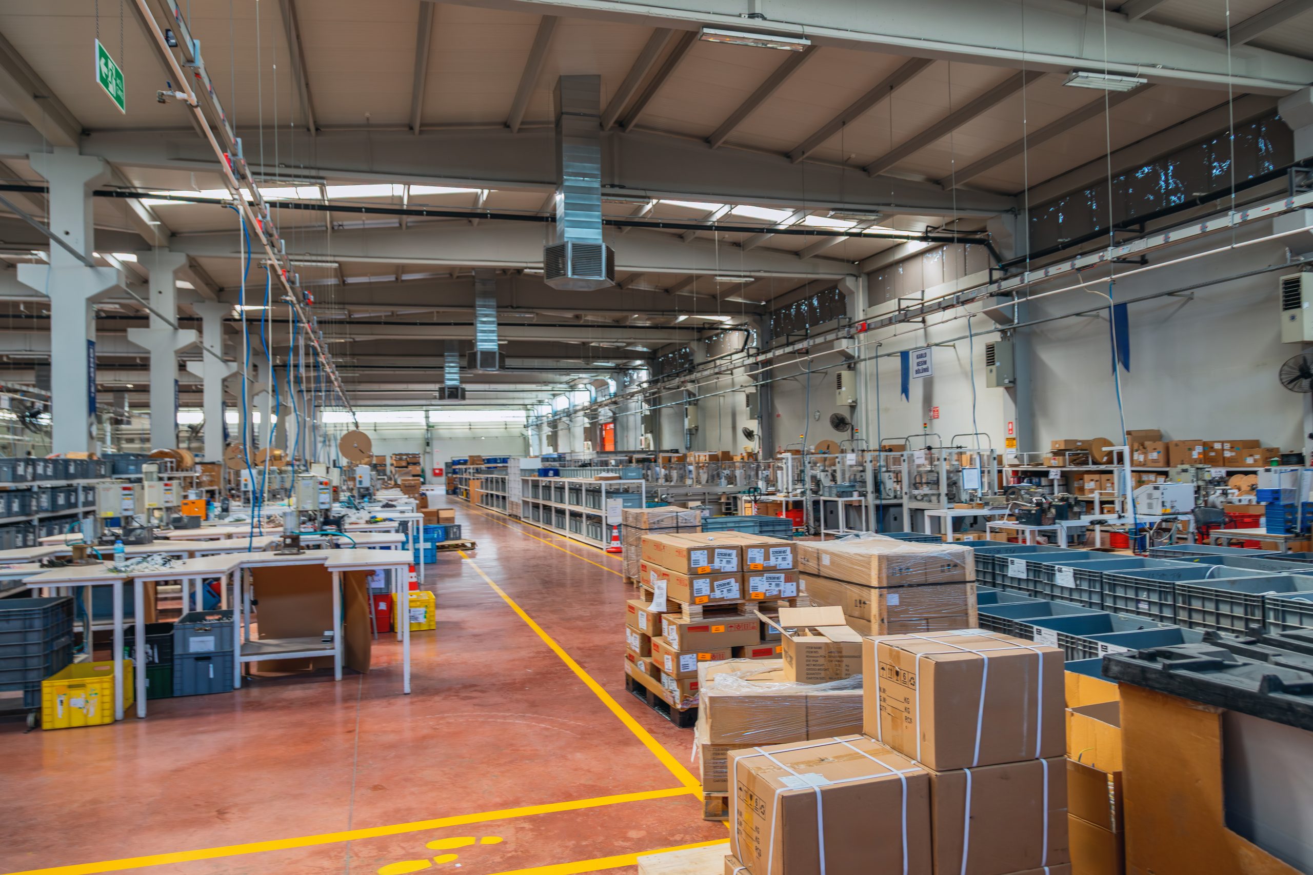 Modern industrial factory interior with production line machinery and packaged cardboard boxes inside manufacturing warehouse