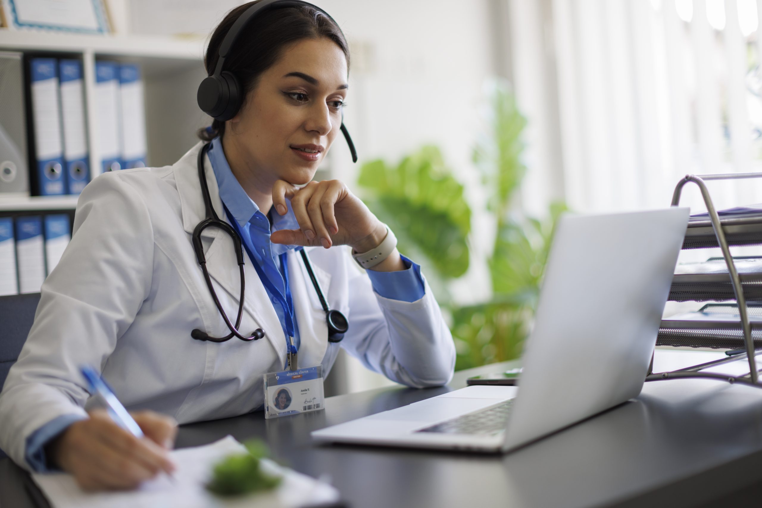 Female doctor using headset and laptop for online consultation