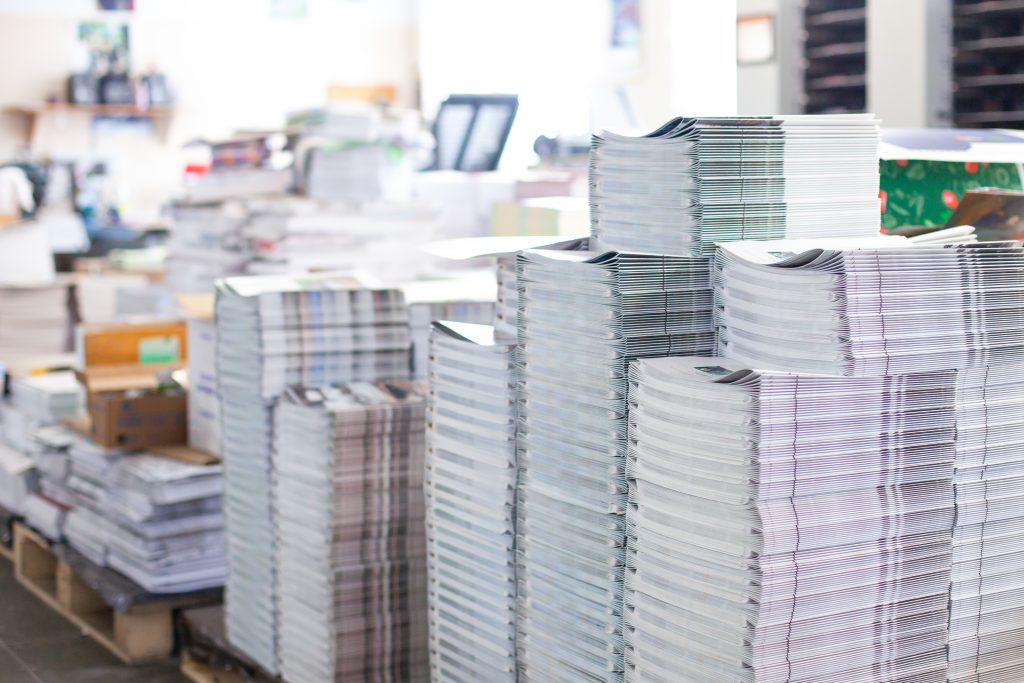 Stacks of printed magazines in commercial print shop.